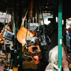 Alte Kameras und Lederetuis hängen an einem Stand. Vintage-Fotografie-Ausrüstung auf dem Flohmarkt, was verkauft sich gut?