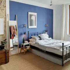 Gemütliches schlafzimmer blau grau mit Metallbett, Kleiderständer und Pflanzen.