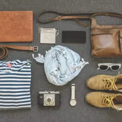 Minimalismus reisen: Ledermappe, gestreiftes Shirt, Schal, Kamera, Uhr, Tasche, Schuhe, Sonnenbrille.