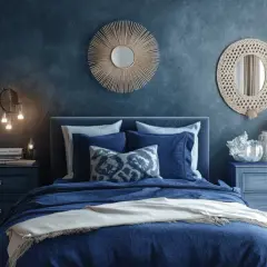 Ein stilvolles Schlafzimmer in Blau und Beige mit einem großen Bett, Spiegeln und Dekorationen.