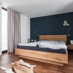 Modernes schlafzimmer blau holz mit einem Doppelbett aus hellem Holz, dunkler Wand und Teppich.