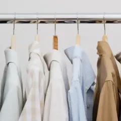 Eine Auswahl an Hemden und einem grünen Pullover für einen stilvollen **capsule wardrobe mann**.