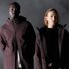 Zwei Models in dunklen Jacken, die Frage "wie viele Jacken braucht man" wird durch die stilvolle Präsentation aufgeworfen.