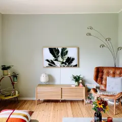 Sanfte Wandfarben Ideen für ein gemütliches Wohnzimmer mit Ledersessel, Pflanzen und Kunst.
