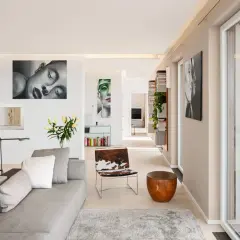 Modernes Wohnzimmer mit Kunstwerken an der wand beige streichen. Graues Sofa, Holztisch, Tierfell-Sessel und Bücherregale.