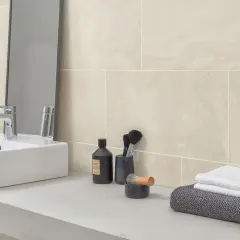 Sandfarbene Badezimmer Fliesen mit natürlicher Maserung, inspiriert von Stein. Ein moderner Waschtisch mit Armatur und Pflegeprodukten.