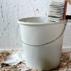 Eimer und Bürste bereit, um Tapeten nass zu machen und die alte Wand zu entfernen.