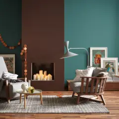 Gemütliches Wohnzimmer mit Kamin, Kerzen und Kunstwerken an den Wänden. Die Wandfarben in Petrol und Braun sind beliebte Wandfarben für ein warmes Ambiente.