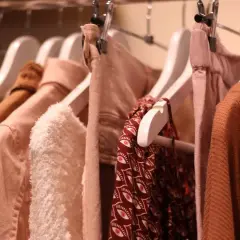 Kleiderbügel mit Kleidung in sanften Erdtönen. Ein Hauch von mode der zukunft in den Texturen und Schnitten.