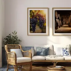 Stilvolle wandgestaltung hinter sofa mit Bildern von Trauben und Weinfässern. Ein Rattan-Sessel und ein Sofa laden zum Entspannen ein.