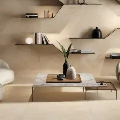 Ein Wohnzimmer in warmen Beigetönen. Ein geschwungenes Sofa und ein Sessel laden zum Entspannen ein. Die Wandfliesen zeigen, wie die Farbe Beige aussieht.