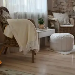 Gemütliches hygge style wohnzimmer mit Korbstühlen, weichen Decken und warmem Licht.