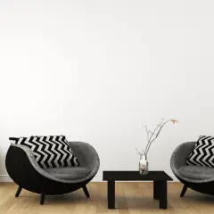 Zwei runde Sessel mit Zickzackkissen, ein kleiner Tisch und ein Nachttisch mit Vasen – ein Einblick in minimalistisch leben erfahrungen.