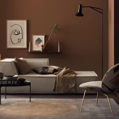 Gemütliches Wohnzimmer mit einer braunen Wand, einem hellen Sofa, einem auffälligen Sessel und einem Couchtisch.