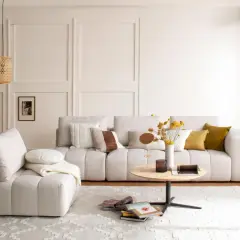 Gemütliches Wohnzimmer mit beiger Couch, Kissen, Couchtisch und Körblampen. Perfekt für slow living einrichtung.
