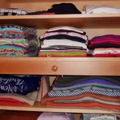 Ordentlich gestapelte Kleidung in einem Schrank. Zeit zum **Kleidung aussortieren** und Platz schaffen für Neues.