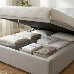 Ein Bett statt Sofa im Wohnzimmer mit viel Stauraum darunter für Bettwäsche.