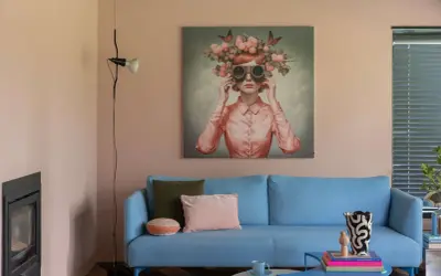 Sanfte Wandfarben im Wohnzimmer harmonieren mit einem blauen Sofa und einem surrealen Kunstwerk.