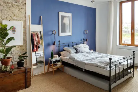 Gemütliches schlafzimmer blau grau mit Metallbett, Kleiderständer und Pflanzen.