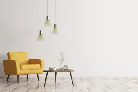 Ein gelber Sessel, ein kleiner Tisch mit Büchern und Deko, drei Hängelampen – ein Raum im extremen Minimalismus.