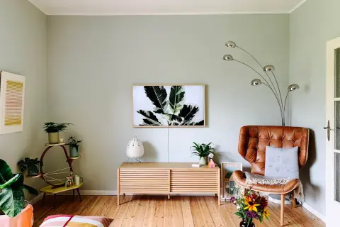 Sanfte Wandfarben Ideen für ein gemütliches Wohnzimmer mit Ledersessel, Pflanzen und Kunst.