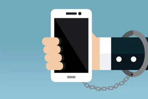 Eine Hand hält ein Smartphone, das mit einer Handschelle und Kette gefesselt ist. Ein Symbol für zu viel Handy-Nutzung.