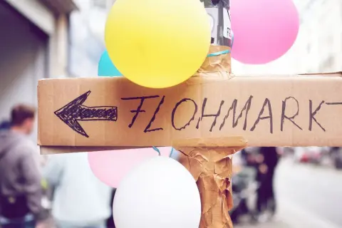 Bunte Ballons und ein handgemalter Pfeil auf Pappe weisen den Weg zum Flohmarkt. Perfekt für deine Flohmarkt-Checkliste!
