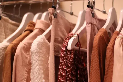 Kleiderbügel mit Kleidung in sanften Erdtönen. Ein Hauch von mode der zukunft in den Texturen und Schnitten.