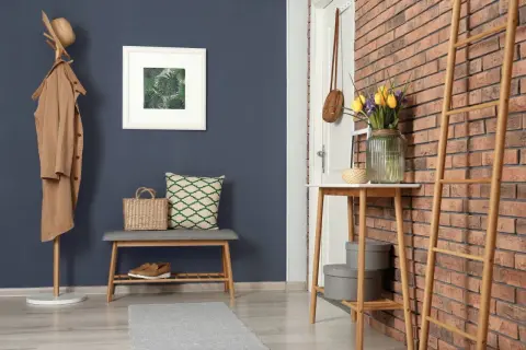 Ein Flur mit dunklem Wandfarben-Trend, Garderobe, Bank, Spiegel und Tulpen.