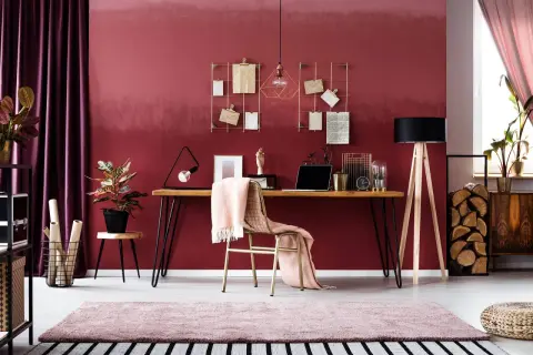 Ein modernes Arbeitszimmer mit einem Schreibtisch, Laptop und einer rosa Decke. Die rosa Wandfarbe wirkt warm und einladend.