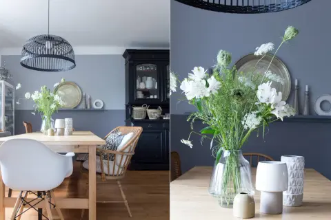 Schöne Esszimmer Wand Ideen: Ein Holztisch mit weißen Stühlen, ein schwarzer Schrank und ein Blumenstrauß.