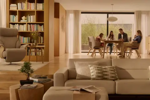 Familie am Esstisch, ein Sessel und ein Sofa in warmen, beigen Tönen. Die beige Wirkung schafft eine gemütliche Atmosphäre.