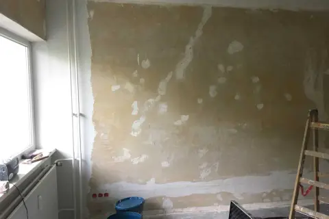 Vorbereitung für das selbst tapezieren: Wand ist vorbereitet, Werkzeug und Eimer stehen bereit.