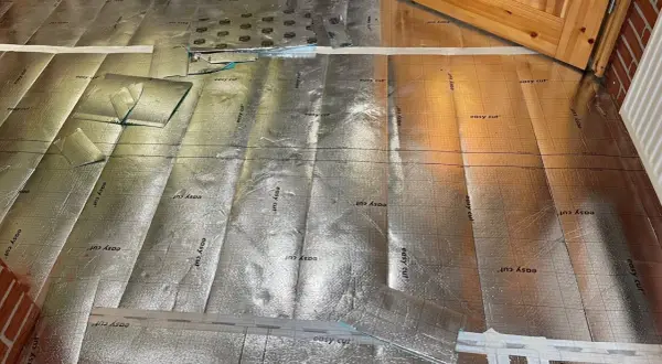 Bodenisolierung mit reflektierender Folie, bereit für die Verlegung im Badezimmer. Kork wird später darauf angebracht.