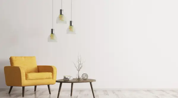 Ein gelber Sessel, ein kleiner Tisch mit Büchern und Deko, drei Hängelampen – ein Raum im extremen Minimalismus.