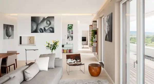 Modernes Wohnzimmer mit Kunstwerken an der wand beige streichen. Graues Sofa, Holztisch, Tierfell-Sessel und Bücherregale.