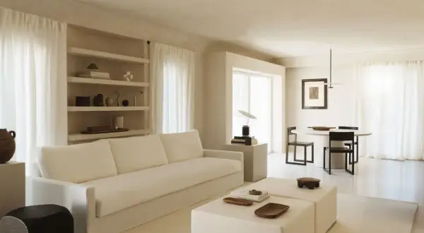Minimalist Wohnzimmer mit weißem Sofa, Beistelltischen und Essbereich. Ein Beispiel für einen modernen Lebensstil, der Ruhe und Ordnung ausstrahlt.