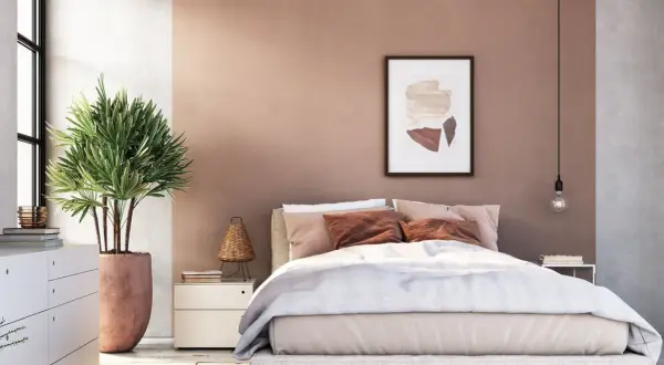 Sanfte Rosatöne und erdige Akzente für deine wandfarben schlafzimmer inspiration. Ein gemütliches Bett mit vielen Kissen und eine grüne Pflanze schaffen Wohlfühlatmosphäre.