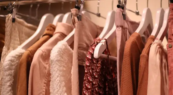 Kleiderbügel mit Kleidung in sanften Erdtönen. Ein Hauch von mode der zukunft in den Texturen und Schnitten.