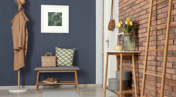 Ein Flur mit dunklem Wandfarben-Trend, Garderobe, Bank, Spiegel und Tulpen.