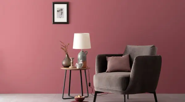 Gemütliche Ecke mit einem Sessel und Beistelltisch. Die Wand in einem warmen, englischen Rosenrot kombiniert mit dunklen Möbeln und Deko.