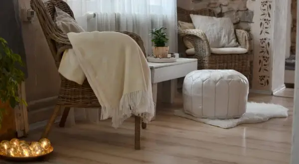 Gemütliches hygge style wohnzimmer mit Korbstühlen, weichen Decken und warmem Licht.