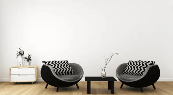 Zwei runde Sessel mit Zickzackkissen, ein kleiner Tisch und ein Nachttisch mit Vasen – ein Einblick in minimalistisch leben erfahrungen.