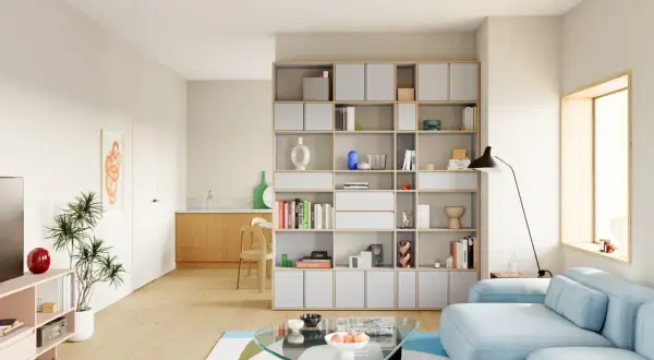Helle, moderne Wohnung mit einem großen Bücherregal, einem blauen Sofa und einem Glastisch. Perfekte Wohnung Inspo für minimalistisches Design.