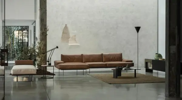 Modernes Wohnzimmer mit Ledersofa, Couchtisch und einem dunklen Boden, der die minimalistische Einrichtung unterstreicht.
