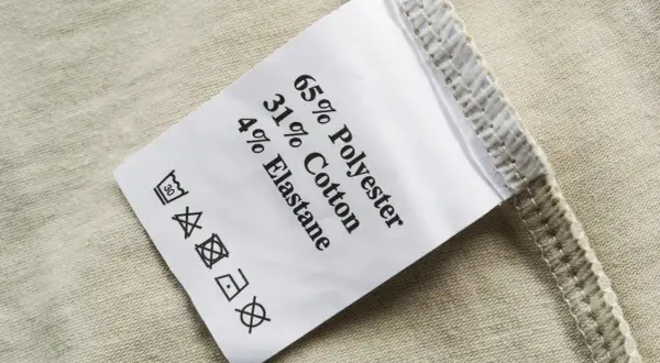 Pflegeetikett mit Materialzusammensetzung: 65% Polyester, 31% Baumwolle, 4% Elastan. Die Textilkette ist gut lesbar.