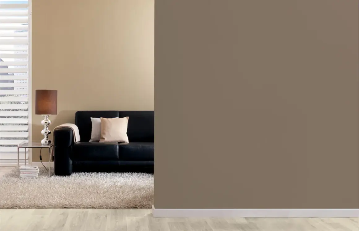Schwarzes Ledersofa mit Kissen, ein Couchtisch mit Lampe und ein flauschiger Teppich. Die Wandfarbe ist braun, eine warme Farbe, die Gemütlichkeit ausstrahlt.