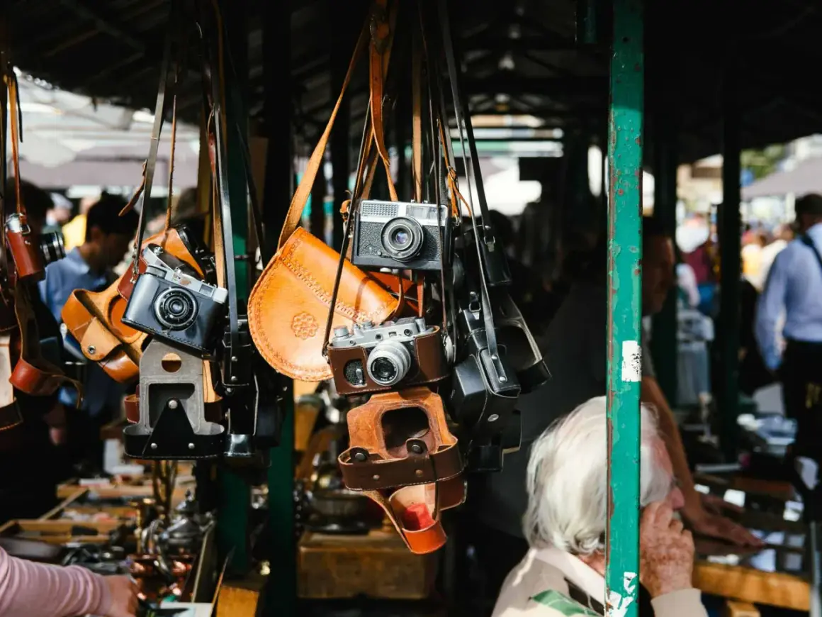 Alte Kameras und Lederetuis hängen an einem Stand. Vintage-Fotografie-Ausrüstung auf dem Flohmarkt, was verkauft sich gut?