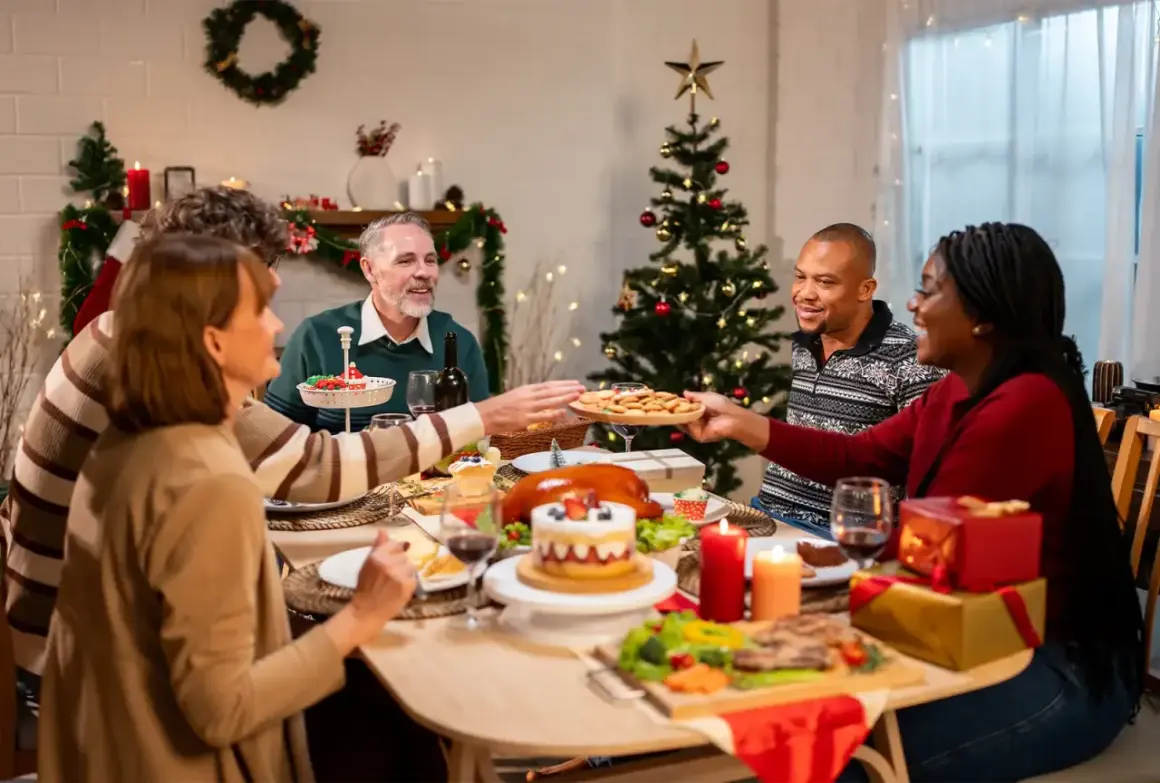 Familie feiert Weihnachten minimalistisch am festlich gedeckten Tisch. Ein Weihnachtsbaum und Kerzen sorgen für stimmungsvolles Licht.