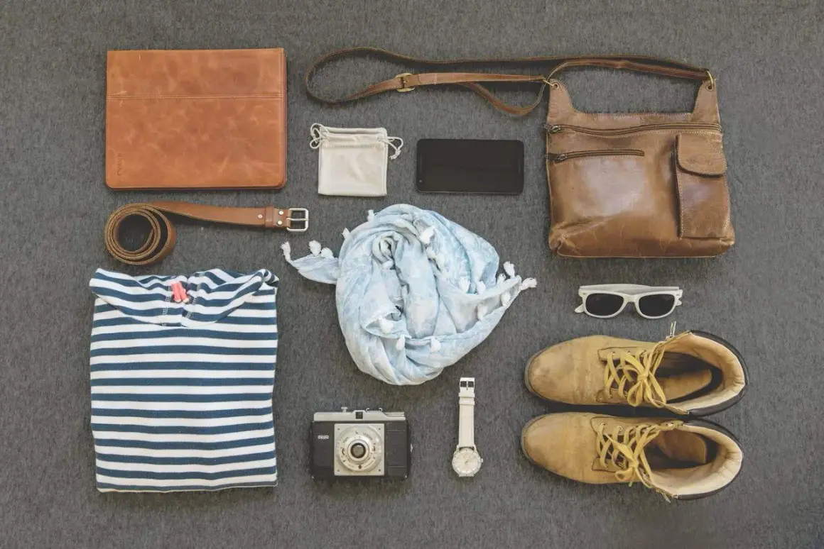 Minimalismus reisen: Ledermappe, gestreiftes Shirt, Schal, Kamera, Uhr, Tasche, Schuhe, Sonnenbrille.